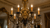 Ornate antique chandelier with candle-style bulbs and hanging crystal prisms in a luxury interior.